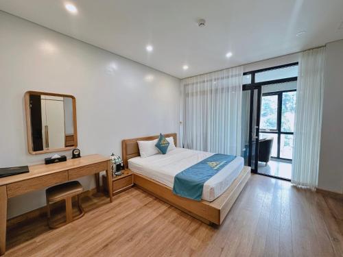 a bedroom with a bed and a desk and a mirror at Queen Hotel Hoàng Gia in Thái Nguyên