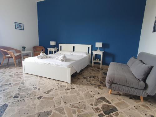 - une chambre avec un lit blanc et une chaise dans l'établissement Angolo del Mare - Case Libeccio e Blu Marino, à Favignana