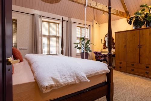 Luxurious Harbour Loft d'Ouwe Moer في روتردام: غرفة نوم مع سرير مظلة في غرفة مع نوافذ