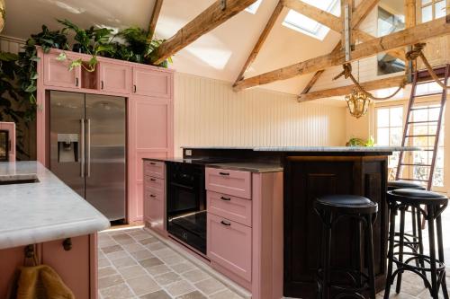 a kitchen with pink cabinets and black appliances at d'Ouwe Moer Apartment in Rotterdam