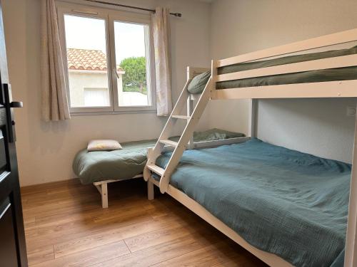 une chambre avec deux lits superposés et une fenêtre dans l'établissement Villa la lagune piscine et spa privés 8 Couchages parking privé et borne de recharge électrique, au Barcarès