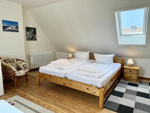 a bedroom with a bed and a chair and a window at Sonneneck in Westerland (Sylt)