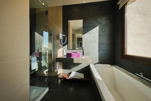 un bagno con vasca, lavandino e specchio di Hotel Spa Villa Nazules a Chueca