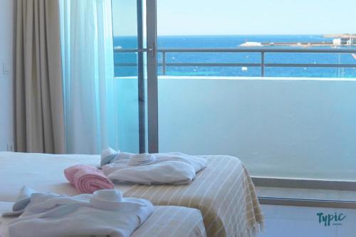 a bedroom with a bed with towels and a window at Typic Marina Playa - Adults Only in San Antonio Bay