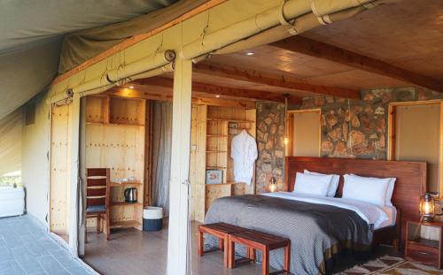 ein Schlafzimmer mit einem Bett in einem Holzzimmer in der Unterkunft Alama Camp Mara in Ololaimutiek