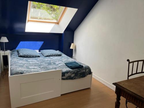 Schlafzimmer mit einem Bett mit blauen Wänden und einem Fenster in der Unterkunft Le Loft, l'annexe in Lorient