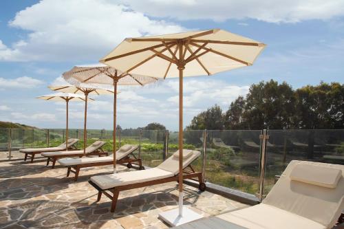 a group of chairs and umbrellas on a patio at Yarden Estate Boutique Hotel in Yesod Hamaala