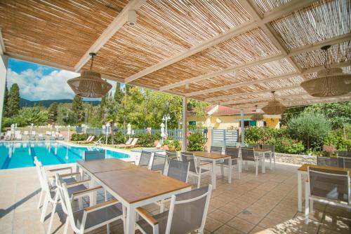 a patio with a table and chairs and a pool at Dominoes Corfu in Ýpsos