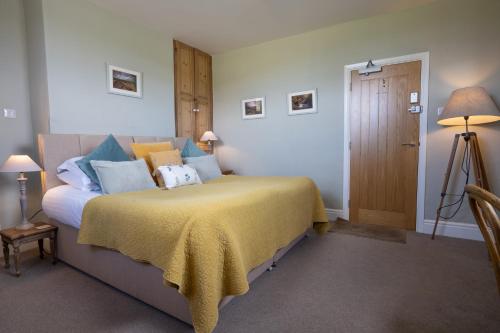 a bedroom with a bed with a yellow bedspread at Hassop Station Apartment on the Monsal Trail in Bakewell