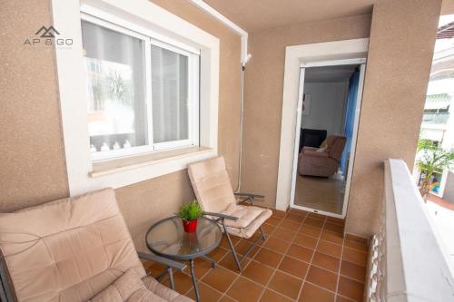 salon z 2 krzesłami, stołem i oknem w obiekcie Fuerte Apartment Great Location w mieście La Herradura