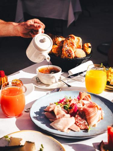a table with plates of food and a person pouring food at Hôtel La Mandarine in Saint-Tropez