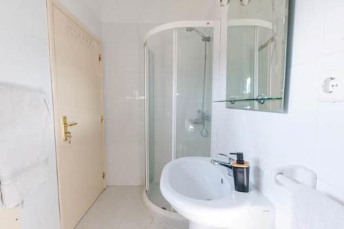 a white bathroom with a shower and a sink at GuestReady - Aragão Guest house in Funchal