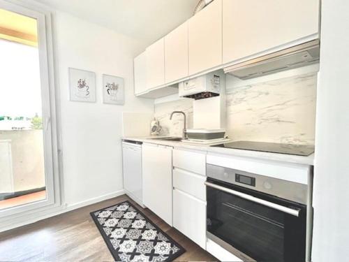une cuisine avec des armoires blanches et un four à plaques de cuisson dans l'établissement Bel appartement lumineux Aix, à Aix-en-Provence