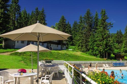 une terrasse avec une table, un parasol et une piscine dans l'établissement Belambra Clubs Les Saisies - Les Embrunes - Ski pass included, à Villard-sur-Doron