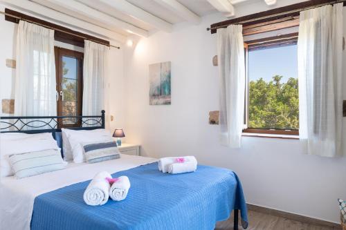 a white bedroom with two beds and a window at Blue Vista Triple Apartment in Skala