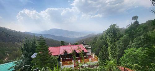 un edificio con techo rojo en la cima de una montaña en Himalayan paradise en Mukteswar