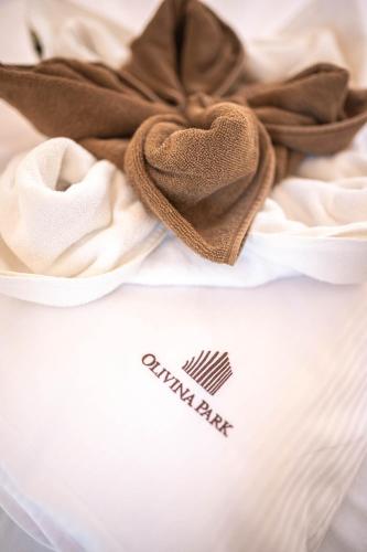 a white shirt with a brown scarf on a bed at Olivina Park Spa - domki z dostępem do krytego basenu, saun, wyżywienia i atrakcji dla dzieci in Niechorze