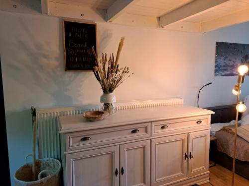 a white cabinet with a vase on top of it at Stad & Strand Appartement in Middelburg