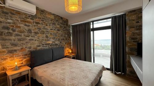 a bedroom with a bed and a brick wall at Aelia Stone Houses in Soúrpi