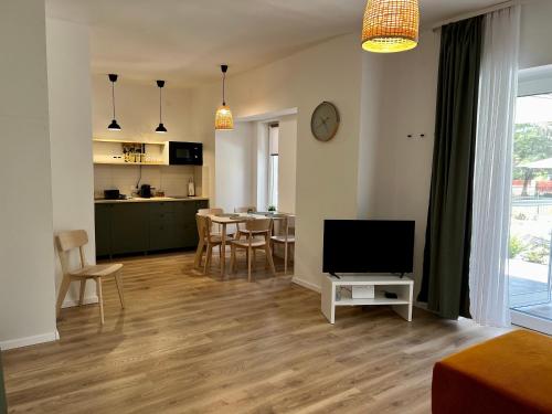een woonkamer met een televisie en een tafel met stoelen bij Best Apartman Boglár in Balatonboglár
