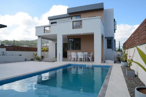 a villa with a swimming pool in front of a house at Casa Blue Print Mahebourg in Mahébourg