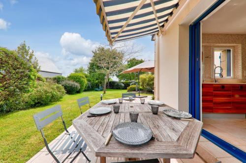 une table et des chaises en bois sur une terrasse dans l'établissement Maison de pierre pour 8 avec beau jardin, à Saint-Gildas-de-Rhuys