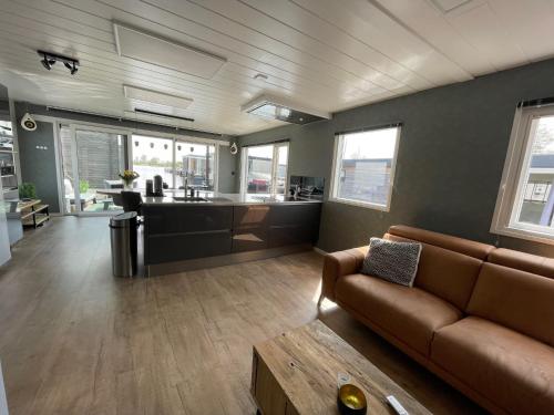 a living room with a couch and a kitchen at Poellodge XL, houseboat met whirlpool en sauna in Aalsmeer