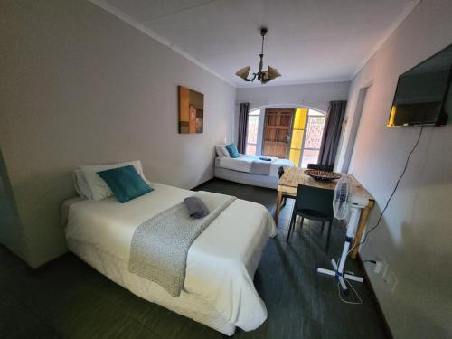 1 dormitorio con cama, mesa y sofá en 29B Zebra Street - InHimwe Guesthouse, en Polokwane
