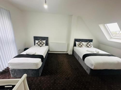 ロンドンにあるBlack Horse Inn Hotelの白い壁と窓が備わる客室で、ベッド2台が備わります。