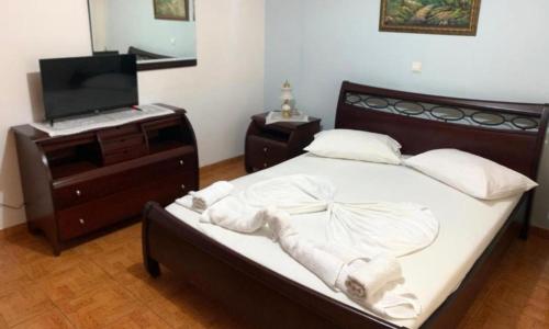 a bedroom with a bed with a dresser and a television at Vila Dura in Ksamil