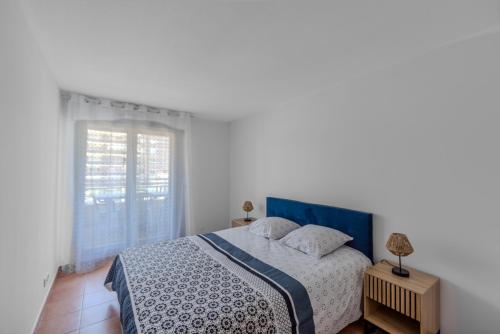 a bedroom with a bed with a blue headboard and a window at Appartement Marina Privée centre-ville Mandelieu in Mandelieu-la-Napoule