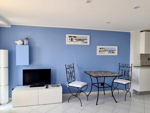 Cette chambre est dotée d'une table, de chaises et d'un mur bleu. dans l'établissement Mentone loft sul mare, à Menton