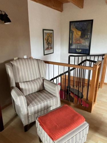 a living room with a chair and a ottoman at Gemütliches Landhaus in ruhiger Lage. in Moringen