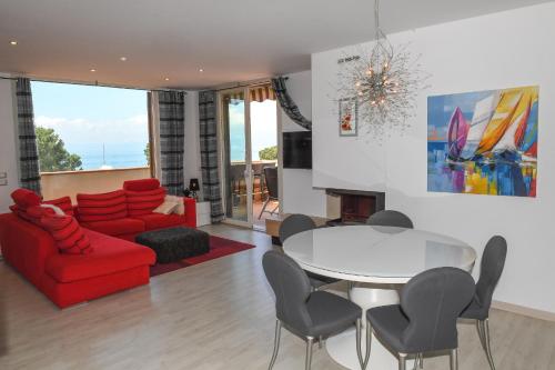 a living room with a red couch and a table and chairs at Favola Bella The panoramic penthouse in Bardolino