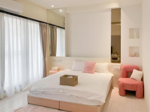 a bedroom with a large bed and a pink chair at 青和漫旅 Ching Ho Inn in Tainan