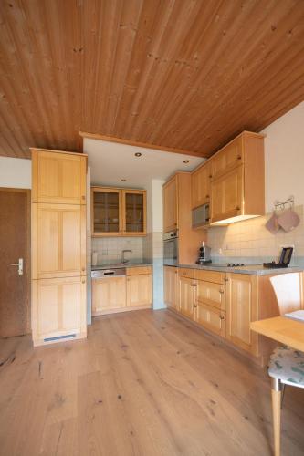 a large kitchen with wooden cabinets and a wooden ceiling at Leindlhof in Kössen