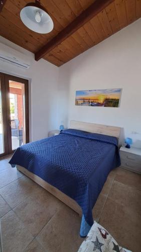a bedroom with a bed with a blue comforter at Villa DEA in Aglientu