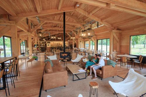 two people sitting in the living room of a wooden building at Huttopia De Meinweg in Herkenbosch