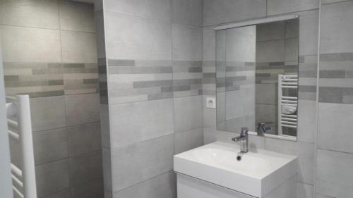 une salle de bain blanche avec un lavabo et un miroir dans l'établissement Appart Must1 Minimes avec Piscine, à La Rochelle
