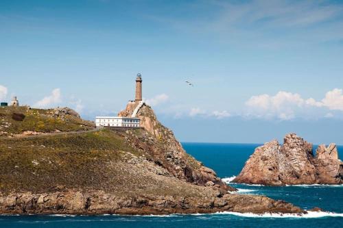 a lighthouse on a rocky island in the ocean at Casa roja in Camariñas