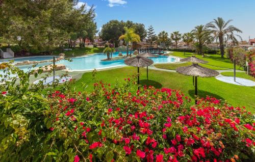 ein Resort mit einem Swimmingpool mit Blumen und Sonnenschirmen in der Unterkunft 3 Bedroom Nice Home In Santa Pola in Santa Pola