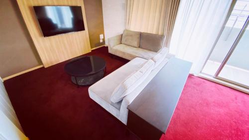 Apartment Hotel 11 Shinsaibashi في أوساكا: غرفة معيشة مع أريكة بيضاء وطاولة