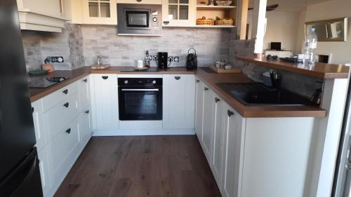 a kitchen with white cabinets and a wooden floor at Cap Saint Martin Marina in Cap d'Agde