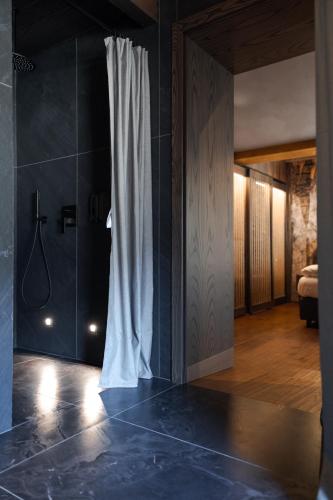a bathroom with a shower and a curtain in a room at Latemar - Hotel Suites Spa in Soraga