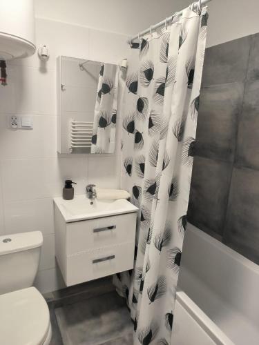 a bathroom with a toilet sink and a shower curtain at Apartament 25 Mikołajki in Mikołajki
