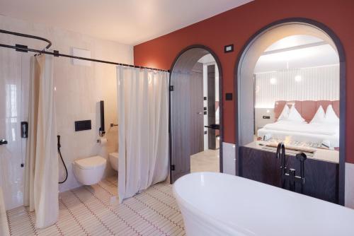 a bathroom with a tub and a shower and a toilet at Latemar - Hotel Suites Spa in Soraga