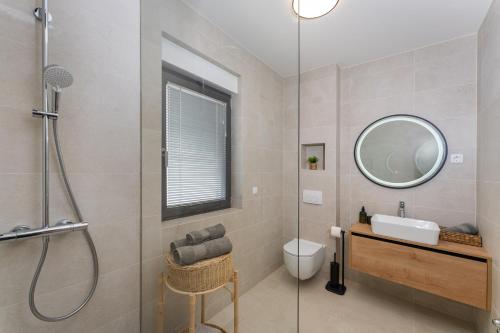 a bathroom with a shower and a sink and a mirror at D Marine villa in Bibinje