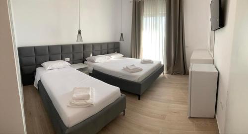 a room with two beds and a flat screen tv at Villa Thomas in Dhërmi
