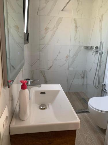 a white bathroom with a sink and a shower at Villa Thomas in Dhërmi