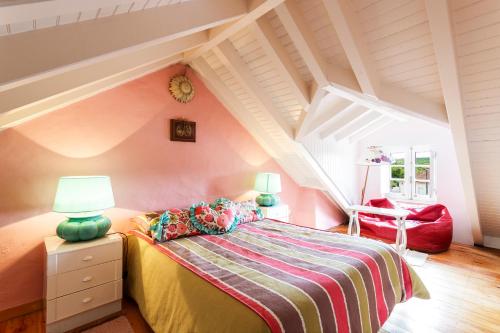 a attic bedroom with a bed and a red chair at WHome Ericeira Private Villa in Mafra